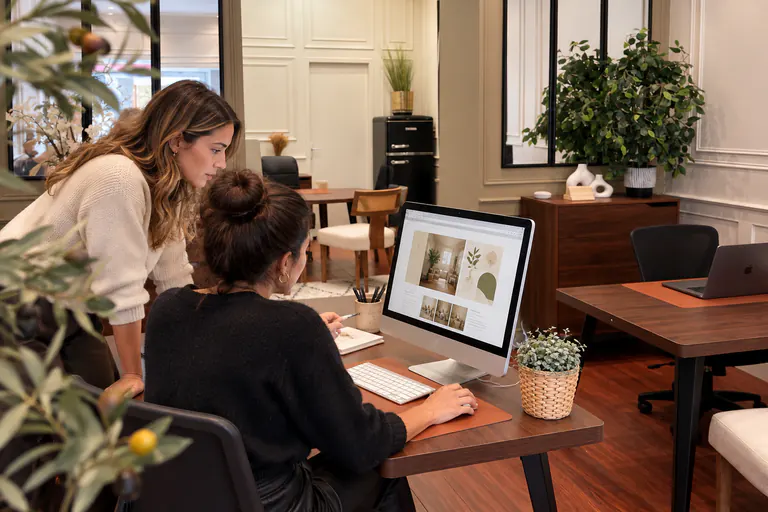 Deux femmes travaillent ensemble sur un écran affichant un site web