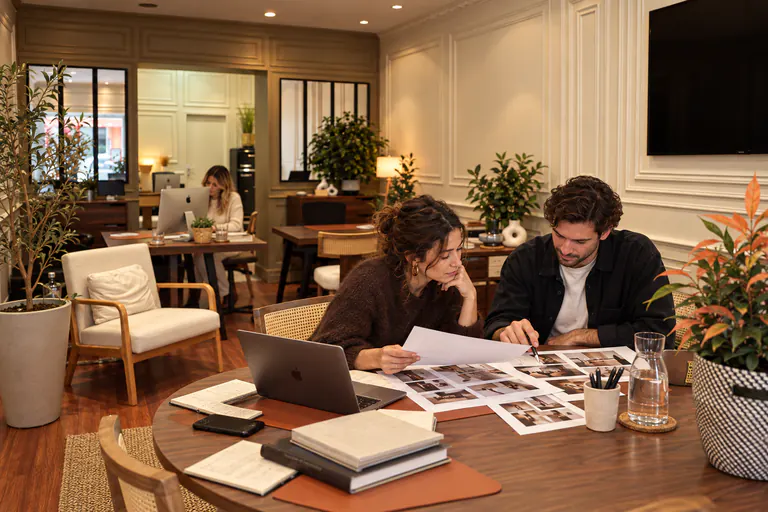 Un homme et une femme examinent des tirages photo posés sur la table
