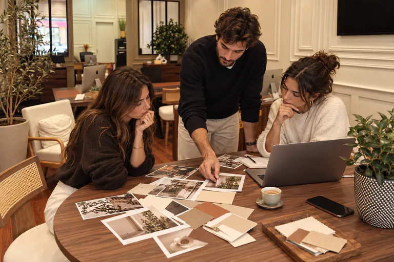 Trois personnes sélectionnent des tirages photo étalés sur une table