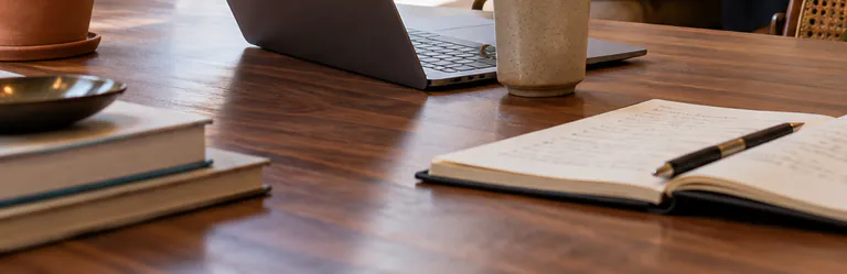 Table en bois avec un ordinateur portable, une tasse et un carnet ouvert