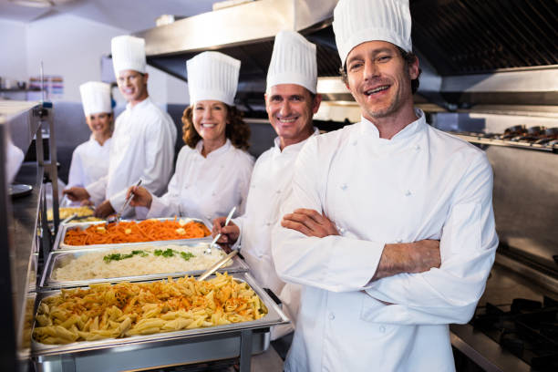 Portrait of chefs standing at serving trays of pasta in commercial kitchen agence SEO cuisiniste à Lyon