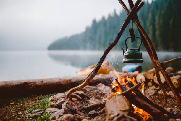 Campfire with a vintage kettle next to the beautiful lake. agence web Camping à Lyon