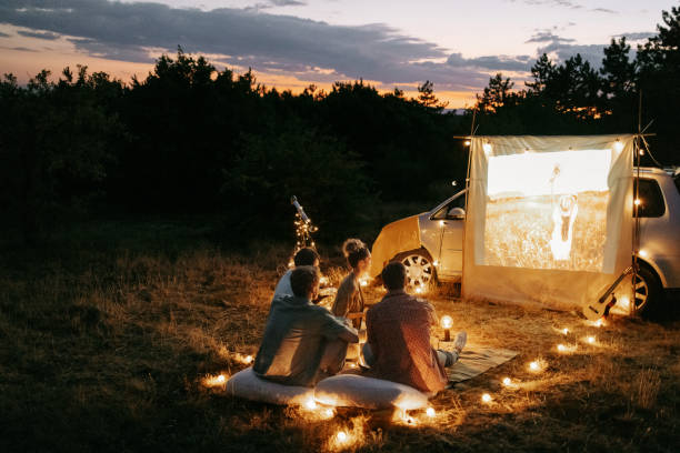 Group of friends enjoying movie night outdoors in nature service web camping à Lyon