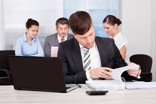 Happy Businessman Sitting In Front Of His Colleagues Working At Desk agence web Sainte-Foy-lès-Lyon