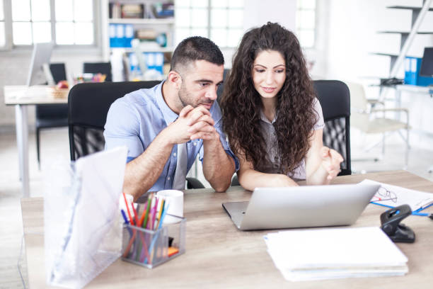 Couple coworkers using laptop at workplace. Agence web Paris 11