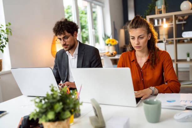 Caucasian female and male coworkers working together at the modern home office agence web Le Marais (Sud)
