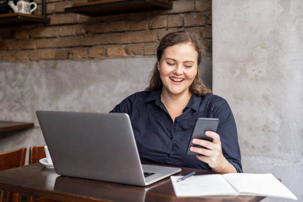 Smiling plus size woman texting on her mobile phone at a local cafe. agence web Jardin des Plantes