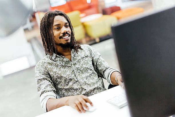 Black handsome designer doing his work on a computer in an office agence web Jardin des Plantes
