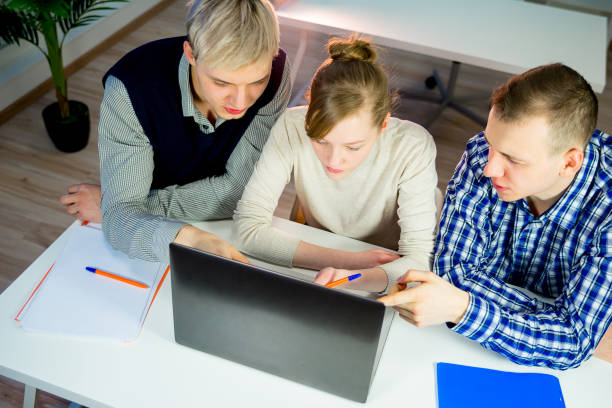 Three students work together with a computer on a project