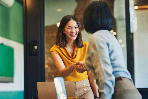 Businesswoman shaking hands with client and smiling cheerfully in meeting room naming entreprise