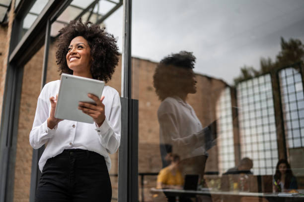 Businesswoman looking away and using digital tablet in an office naming entreprise